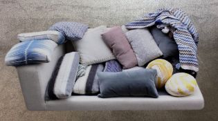 A large collection of scatter cushions and a woven tassled throw.