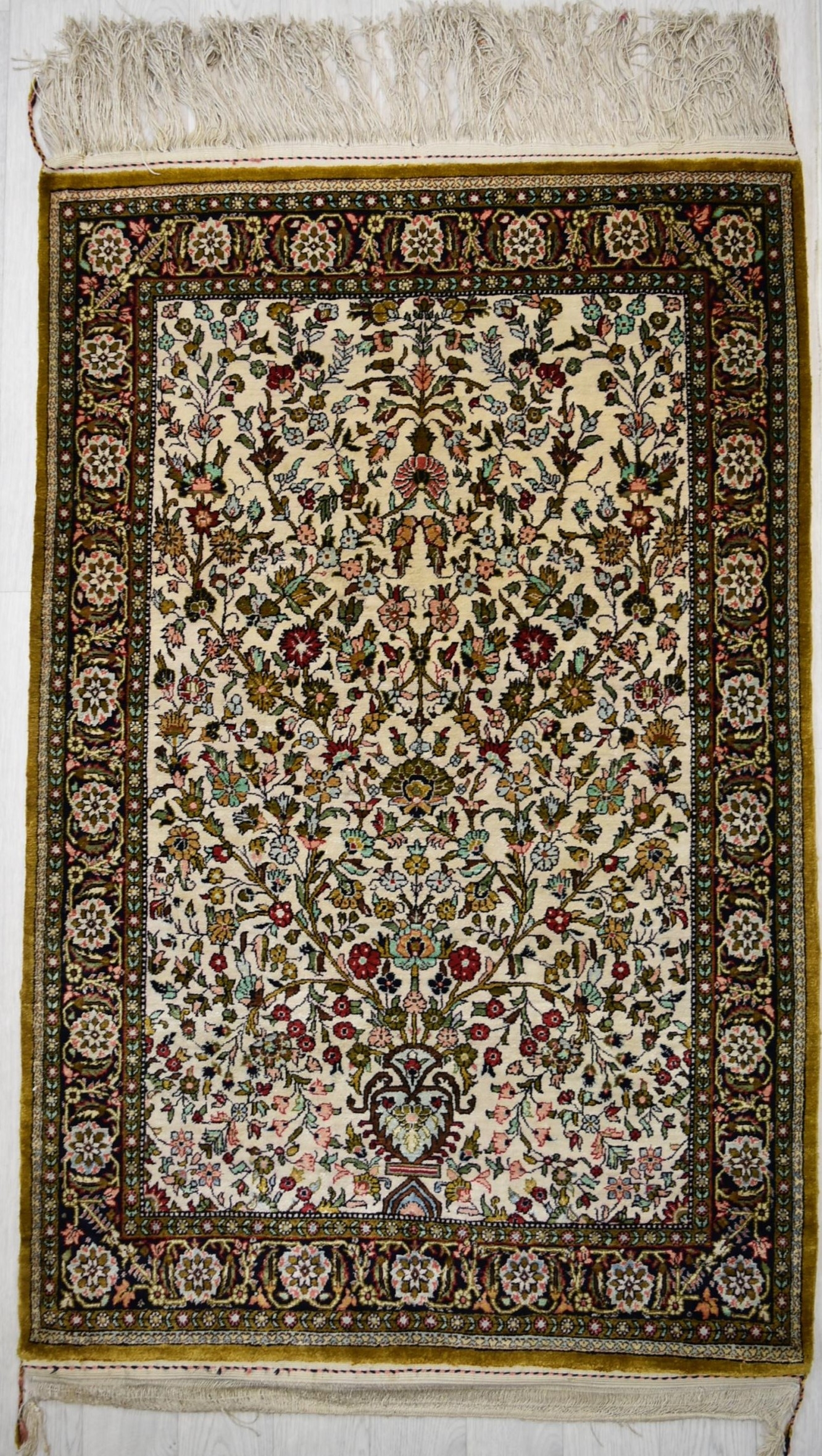 A Persian/Iranian silk Qum (Qom) rug, the central ivory field with tree of life within floral