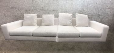 A large contemporary white cotton upholstered four seater settee, in two parts.