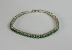 A boxed silver green stone set tennis bracelet with secure lobster clasp. Stamped 925. L.20cm