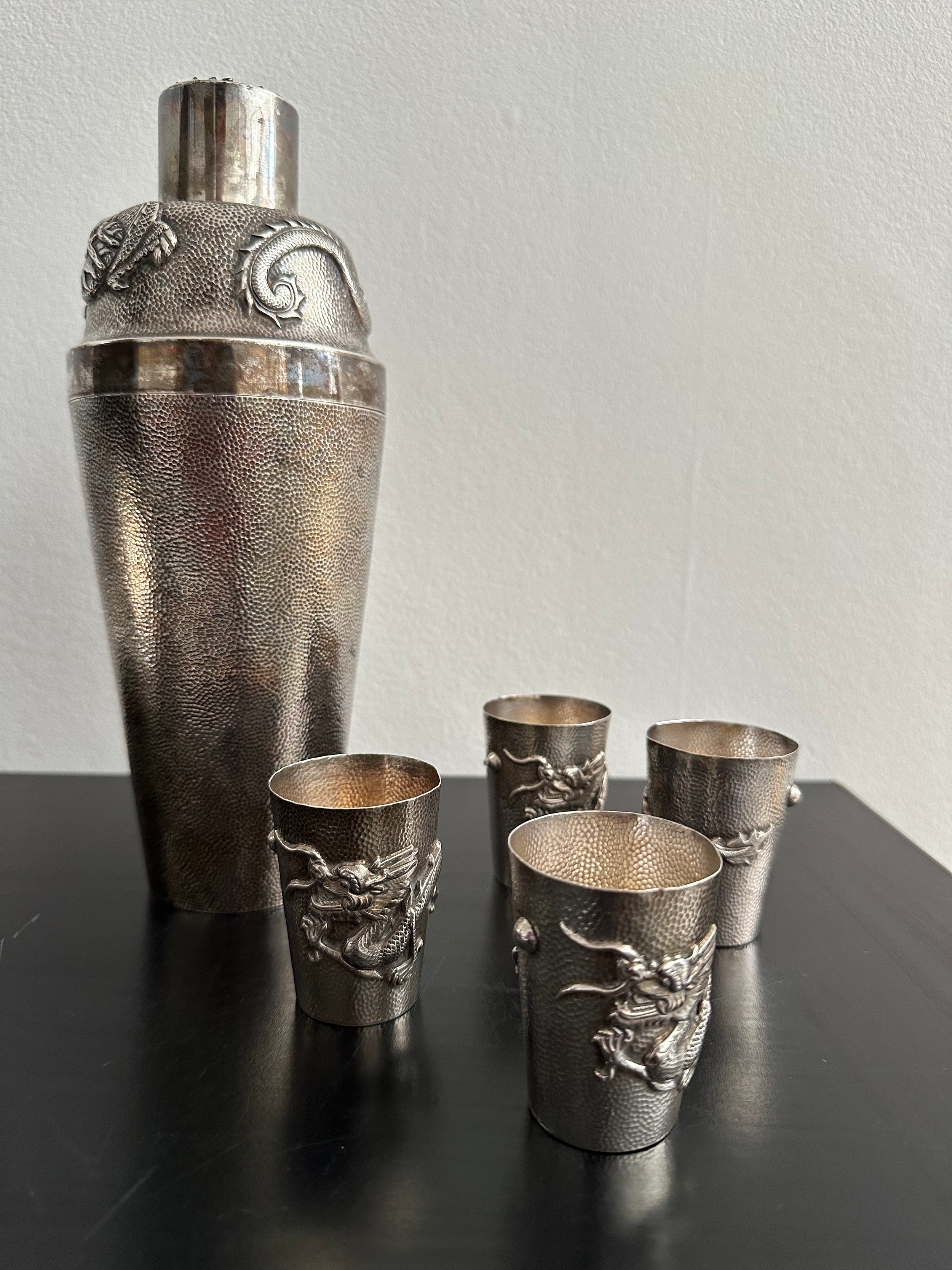 A Chinese silver repousse cocktail shaker and four matching shot glasses. The cocktail shaker