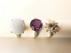 Three 20th century 10 carat gold gem-set rings: an amethyst and white topaz flanked solitaire