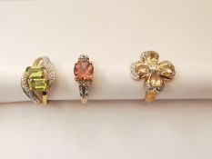 Three 20th century 9 carat gold gem-set rings, one with a cross over design set with peridot and