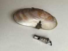 An early 20th century clam shell hinged purse with red lining along with a French miniature whistle.