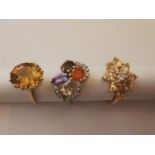 Three 20th century 10 carat yellow gold gem-set rings: a imperial topaz solitaire ring, a floral