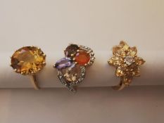 Three 20th century 10 carat yellow gold gem-set rings: a imperial topaz solitaire ring, a floral