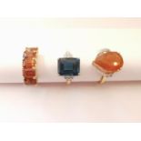 Three 20th century 10 carat gold gem-set rings: a blue topaz flanked solitaire ring, a diamond and
