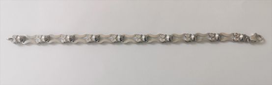 A contemporary 18 carat white gold articulated teddy bear and infinity link bracelet with secure