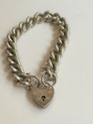 A chunky silver curb link charm bracelet with heart shaped padlock clasp and safety chain.