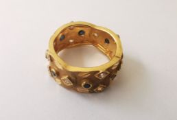 A 22 carat yellow gold wide scalloped band set with clear and black stones, engraved detailing the