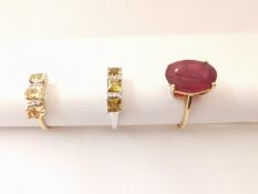 Three 20th century 10 carat gold gem-set rings: a solitaire ring set with an oval mixed cut ruby