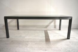 A contemporary brushed steel and glass topped occasional table raised on square supports. H.41 W.122