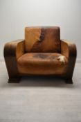 A walnut framed Art Deco leather armchair, the arms and back with integrated shelves. H.86.5 W.111.5