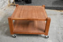A contemporary hardwood low table on casters. H.48 x W.72 x D.72cm