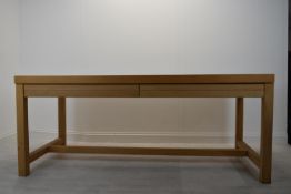 A contemporary oak four drawer refectory style table raised square supports united by a stretcher