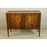 A late 18th/early 19th Sheraton style mahogany twin door cabinet opening to reveal shelves, raised