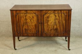 A late 18th/early 19th Sheraton style mahogany twin door cabinet opening to reveal shelves, raised