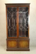 A C.1900 Georgian style mahogany twin glazed door bookcase above twin panelled door standing on