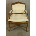 A Louis XV style walnut framed open armchair with bergere back, raised on carved cabriole supports