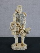 A Japanese Meiji period (1868-1912) carved bone okimono travelling salesman raised on incised oval