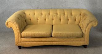 A 19th century mahogany framed button back yellow upholstered two seater settee raised on turned
