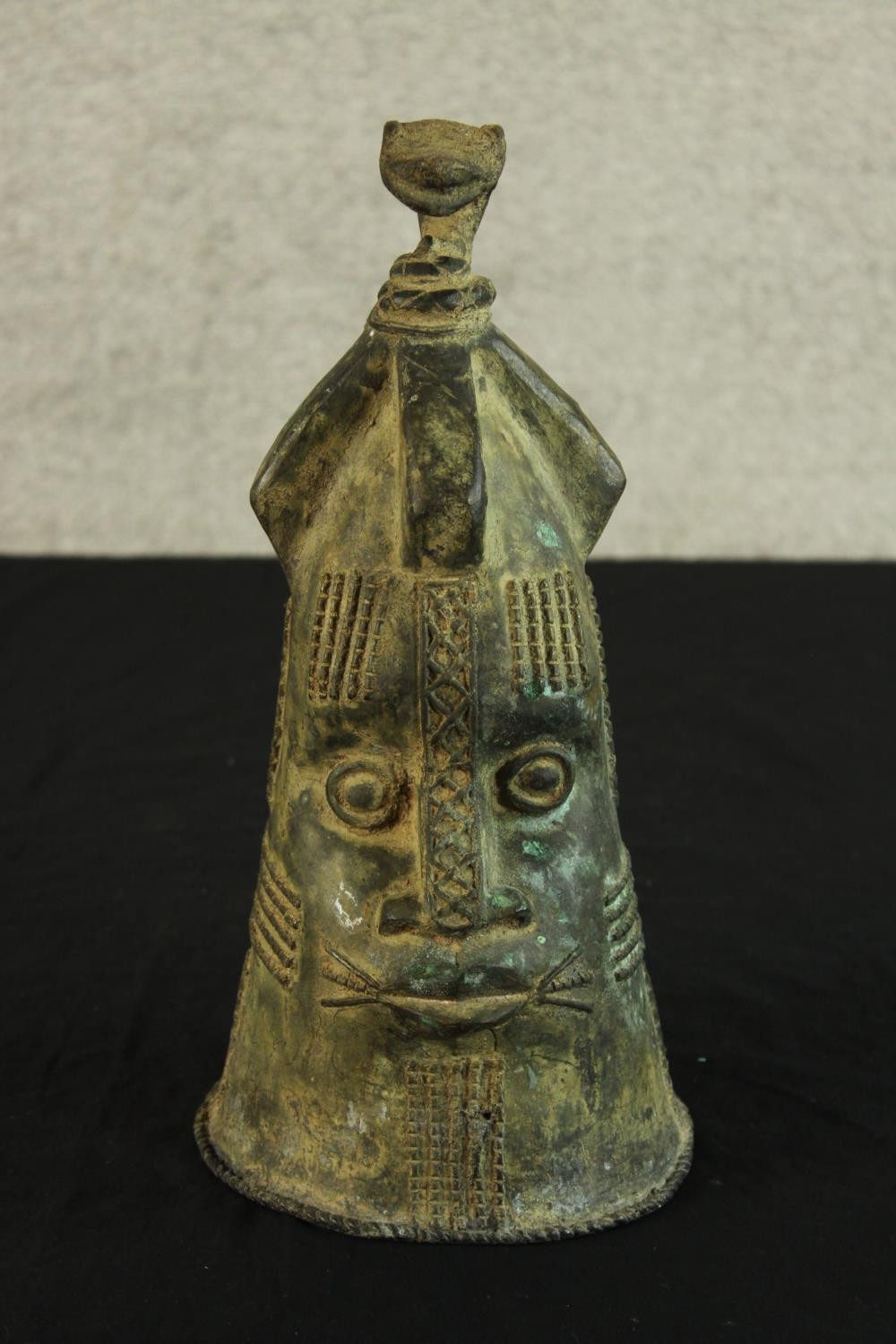 A Japanese possibly Edo period cast bronze bell modelled in the form of a stylised head. H.36cm.