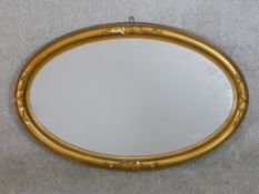 A C.1900 plaster gilt painted oval mirror with applied ribbon and swag decoration. H.53 W.75cm