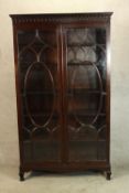 An early 20th century S & H Jewell mahogany twin door glazed bookcase with adjustable shelves raised