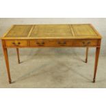 A Georgian style walnut writing table with three drawers raised on tapering supports terminating