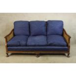 A mid 20th century mahogany framed bergere three seater settee raised on short cabriole supports