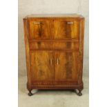 An Art Deco style fitted walnut drinks cabinet, with accessories above two cupboard doors standing