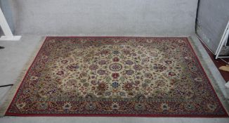 A 20 century Persian silk carpet, the central ivory field with floral decoration within red ground