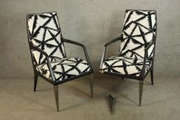 A pair of 20th century lacquered framed upholstered open arm chairs raised on tapering supports. (