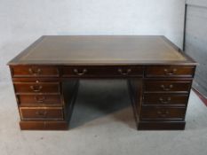 A 20th century stained mahogany twin pedestal partners desk with brass swing handles raised on