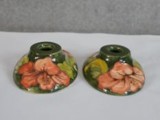 A pair of 20th century Moorcroft pottery oval squat candlesticks, tubelined with hibiscus decoration