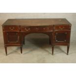 A Sheraton style mahogany serpentine fronted desk with three drawers with cupboards below raised