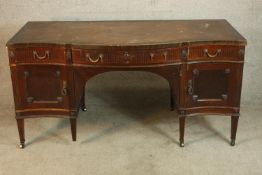 A Sheraton style mahogany serpentine fronted desk with three drawers with cupboards below raised