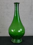 A mid 20th century green glass floor standing pear drop shaped vase raised on circular foot. H.64