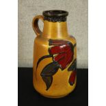A mid 20th century West German pottery pitcher jug tubelined with floral decoration, marks to