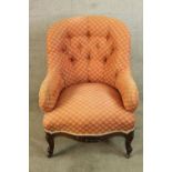 A 19th century carved mahogany framed button back low nursing chair raised on carved cabriole