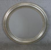 A contemporary sllver painted circular wall mirror. H.78 W.78cm