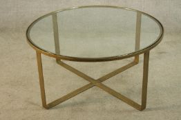 A contemporary circular brass framed glass topped low table raised on X shaped base. H.47 Dia.97cm.