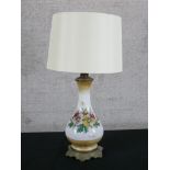 An early 20th century painted milk glass baluster shaped table lamp decorated with flowers, raised