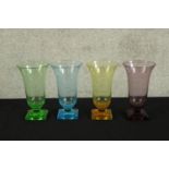A set of 1930s Art Deco coloured glass trumpet shaped vases raised on stepped square bases.