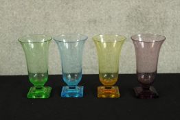 A set of 1930s Art Deco coloured glass trumpet shaped vases raised on stepped square bases.