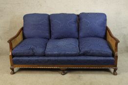 A mid 20th century mahogany framed bergere three seater settee raised on short cabriole supports