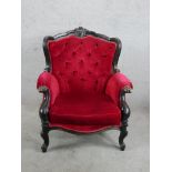 A 19th century ebonised framed deep button back upholstered wingback chair raised on carved cabriole