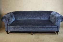 A late Victorian mahogany framed blue upholstered scroll arm settee raised on turned bun feet and