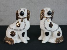 A pair of late 19th century painted Staffordshire pottery seated dogs, each with gilt painted