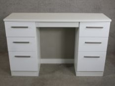 A contemporary white twin pedestal writing desk with brushed chrome plated handles raised on
